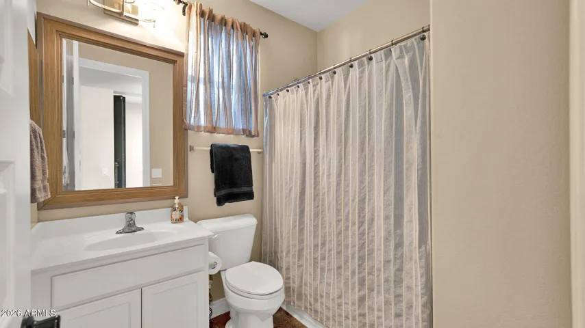 Guest bathroom with tub/shower combination, single-sink vanity, designer mirror and lighting.