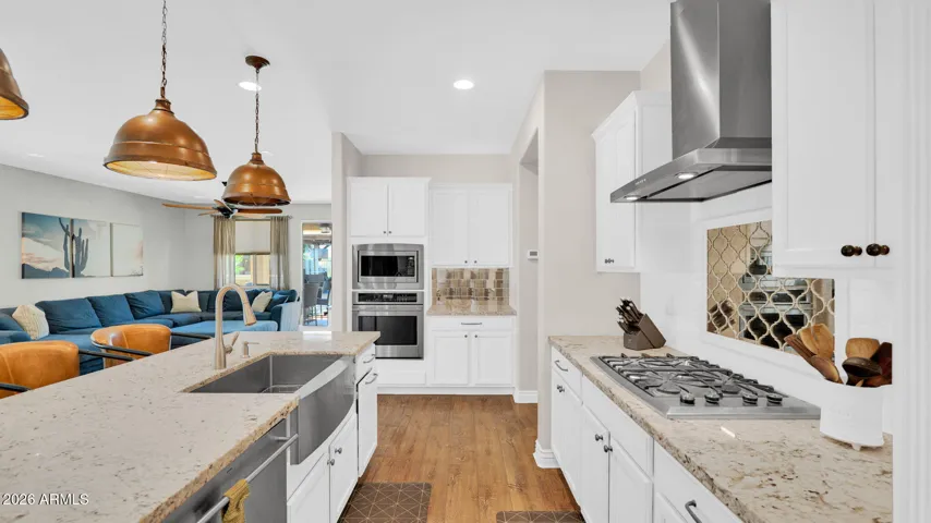 Chef’s kitchen featuring a gas cooktop, stainless steel hood, and designer backsplash, combining function and style for everyday cooking and entertaining.