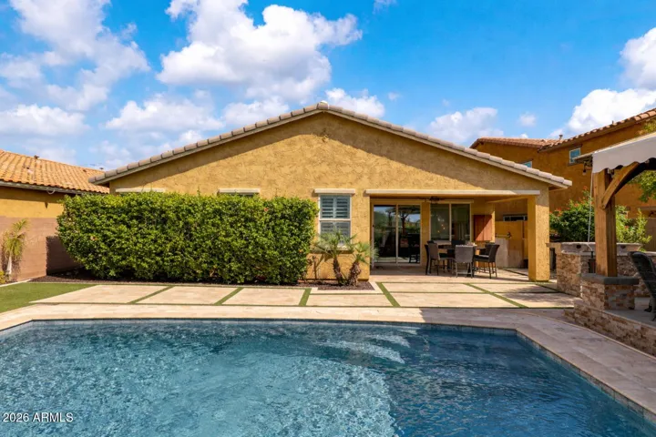 Backyard design combines travertine walkways with artificial turf accents, creating a clean, low-maintenance space that balances style and function around the pool.