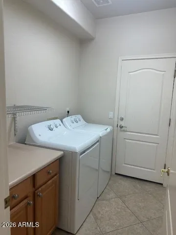 The laundry comes with a washer and dryer plus a base cabinet and shelves.