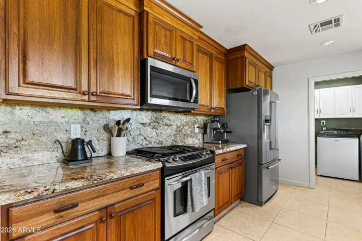 Bright and open kitchen leads to the laundry room. Kitchen has gas range, chef inspired cooktop, microwave hood, and plenty of natural light.