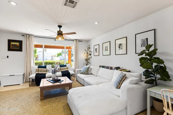 Bright and inviting living room off the entry with windows, new low voltage lighting, custom ceiling fans and wains-coating wall and chair rail. Modern design with a touch of country.
