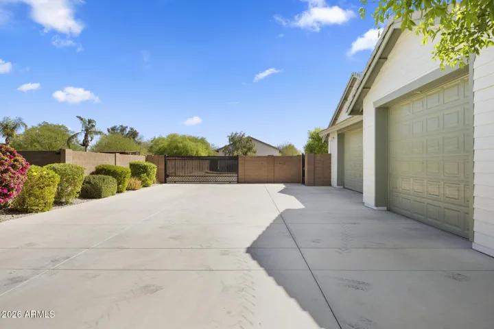 driveway for the attached three car garage that leads to an additional detached garage beyond the electronic powered gate