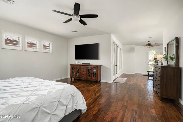 Serene primary retreat with space for a sitting area, large windows, and warm wood flooring, offering a peaceful escape in this beautifully upgraded Phoenix residence.