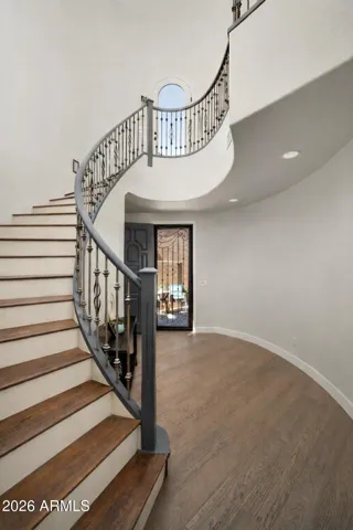 Elegant entry foyer showcasing a dramatic curved staircase and soaring ceilings, creating a striking first impression in this Phoenix home.