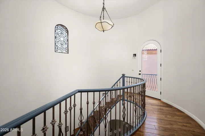 Spacious upper landing with wrought iron railing and Juliet balcony, enhancing architectural charm and natural light in this Phoenix residence.