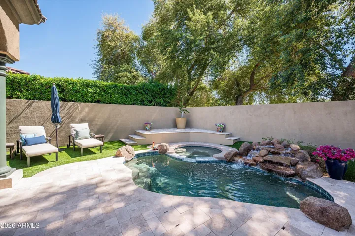 Tranquil backyard pool with waterfall feature, spa, and updated tile, offering a the perfect experience for relaxing and enjoying Phoenix outdoor living.