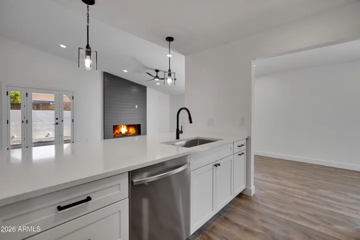 Kithen view into Great room, quartz counter, double sided cabinets, stainless washer & sink.