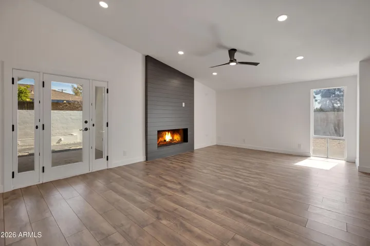 Great room with ship lap accented gas fireplance valuted ceiling, ceiling fan, access to side yard & storage rooms.
