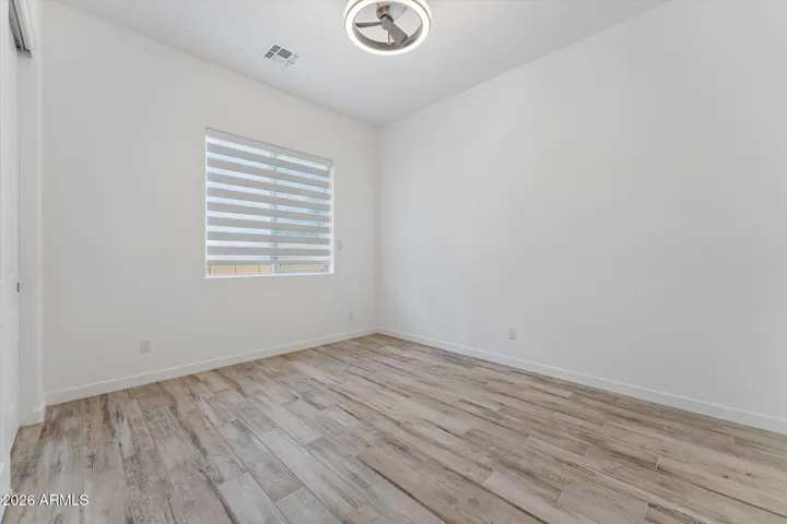 Large guest bedroom with Tile Floors, Motorized Blinds, and Modern fan/light.