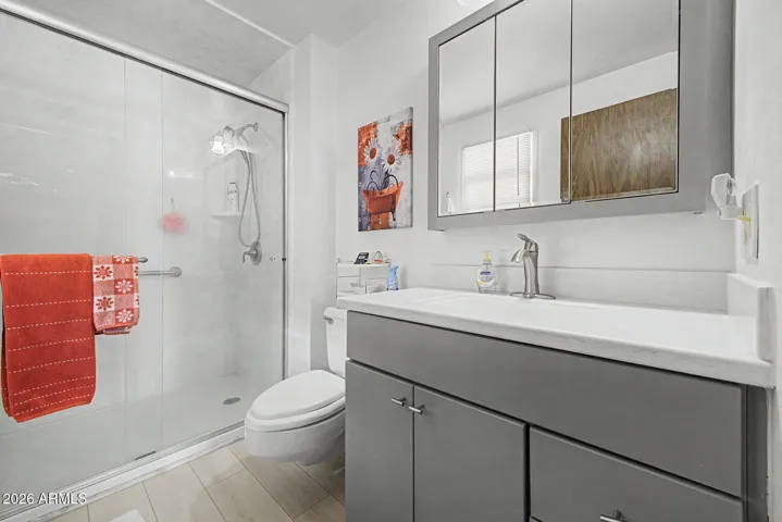 Primary Bath completely remodeled with easy step in glass shower, gray cabinets, laminate flooring & mirror.