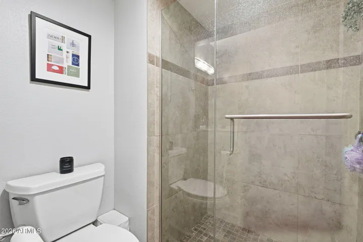 Tiled shower with Glass enclosure. There's a large wall closet on the opposite wall.