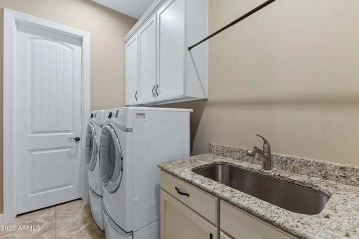 Spacious laundry room with sink and large storage closet.