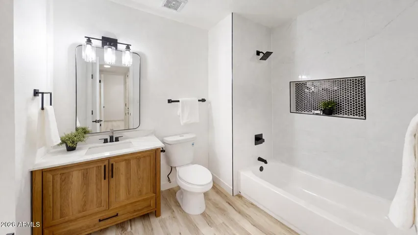 Fully remodeled bathroom with modern vanity, tiled shower/tub combo, and sleek black finishes