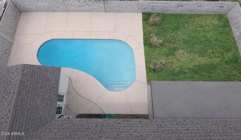 Oversized pool with expansive patio space and additional grass area for outdoor living