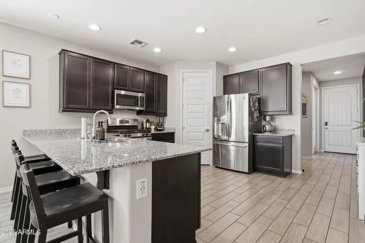 Open Kitchen with stainless appliances, pantry, gas stove, granite countertops and peninsula style island.
