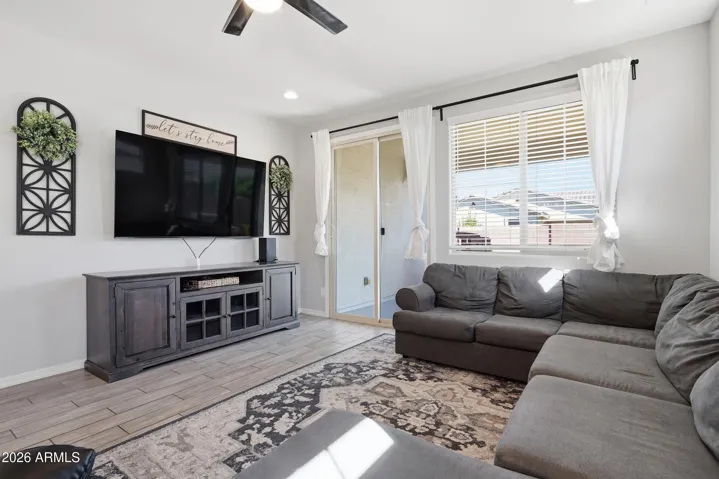 Open Great room with room for a large sectional, ceiling fan and a view to the backyard