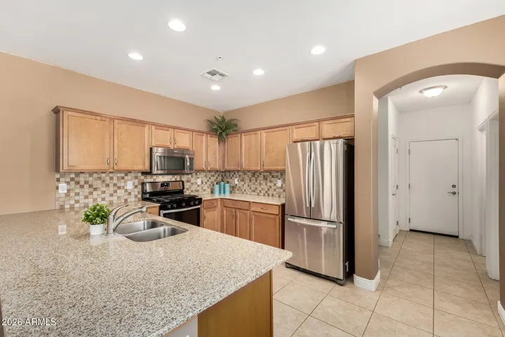 The adorable kitchen features an abundance of cabinetry for storage, complemented by sleek stainless steel appliances.