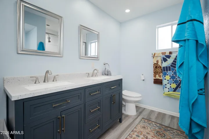 Updated bathroom off 2nd primary bedroom has 2 sinks, quartz counters, framed mirrors, tile floors + gorgeous tiled shower with glass surround.