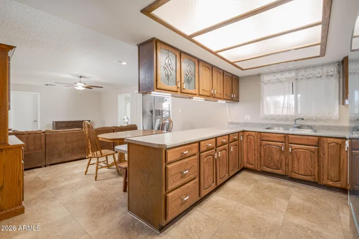 Spacious kitchen featuring bright over-sink window, glass front decorative cabinets + plenty of counter space.