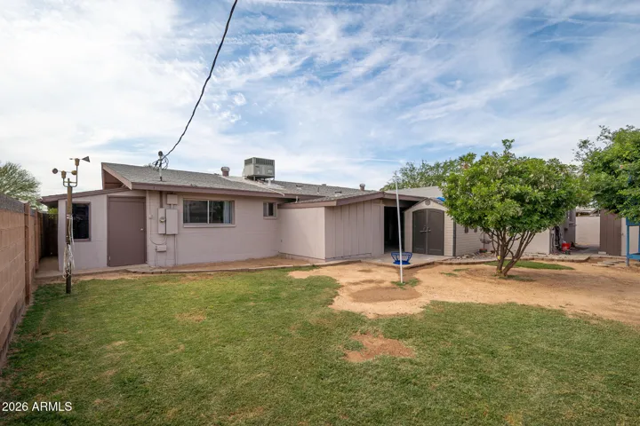 Spacious back yard with grass and mature trees. Door leads to separate storage area. (see next picture)