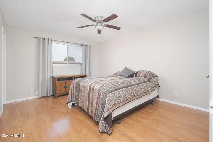 1st primary bedroom with laminate wood floors, ceiling fan + walk-in closet.