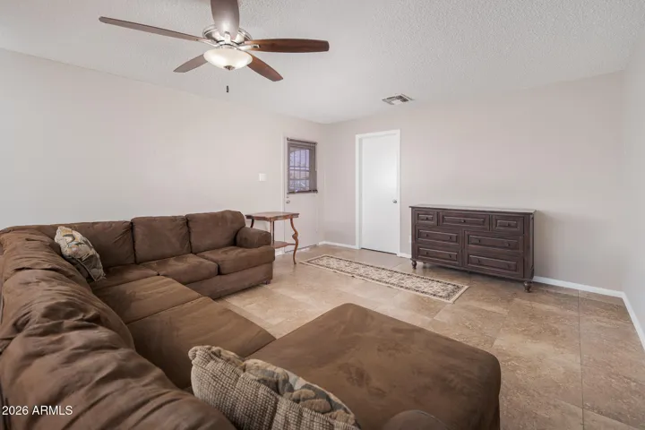 Spacious family room with 20x20 neutral tile flooring + ceiling fan. (Door leads to large den/office space OR could be bedroom 5. There IS a closet, but no window.)