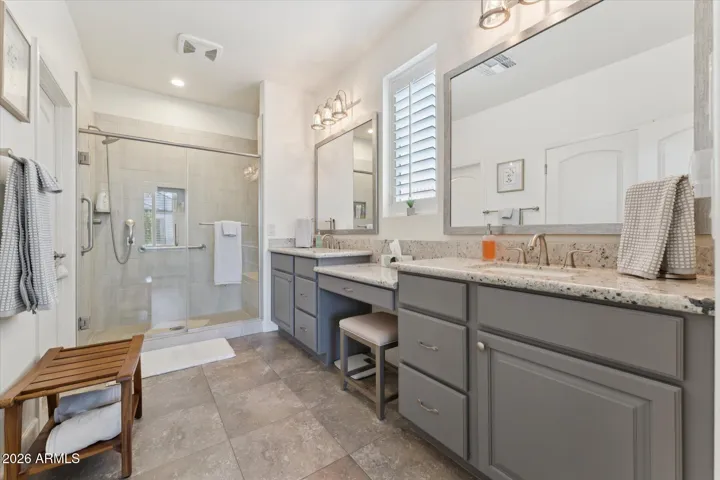 Primary en-suite bath has granite countertops, dual vanity, step in tiled shower with grab bar