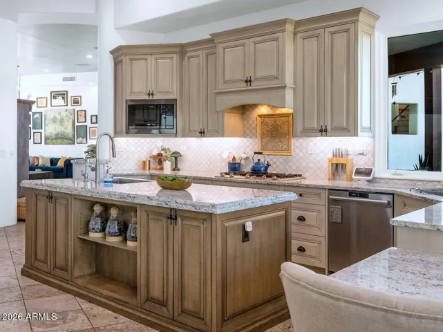 Rich custom cabinetry, granite countertops, and a spacious center island perfect for gathering and entertaining. A stylish backsplash, built-in appliances, and ample storage make it as practical as it is inviting.