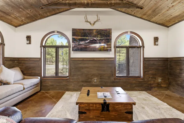 Open concept living space with wood beam ceilings, stained concrete floors, and plenty of natural light.