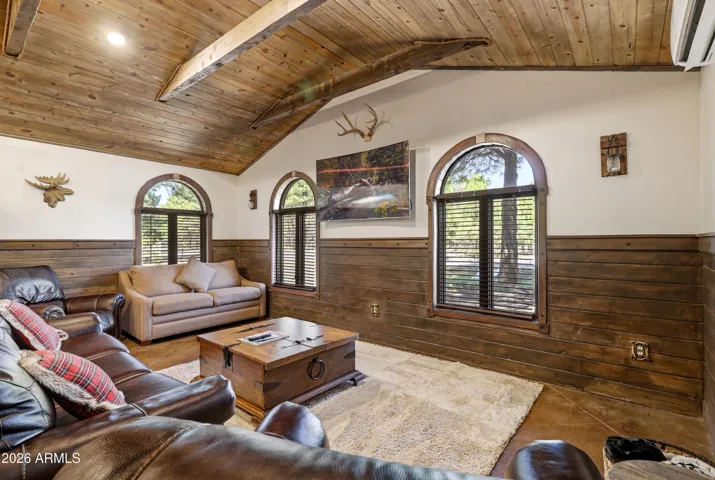 Open concept living space with wood beam ceilings, stained concrete floors, and plenty of natural light.