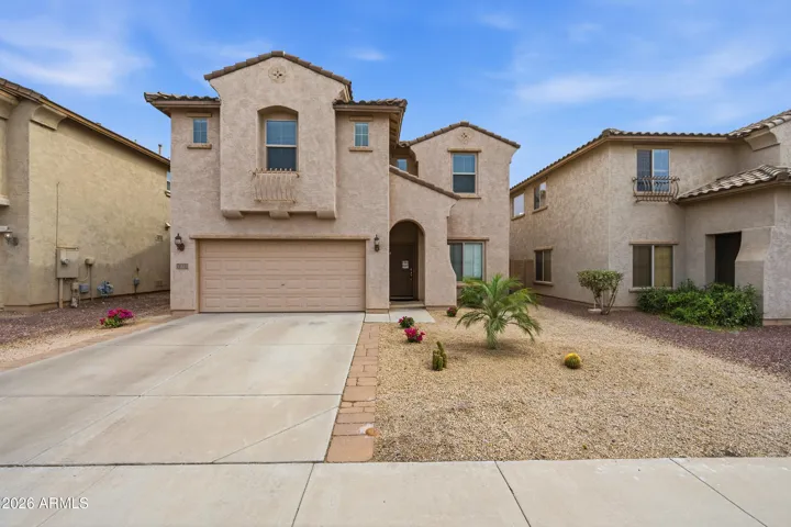 Beautiful daytime curb appeal featuring a two-story Mesa home with a classic stucco exterior, tile roof accents, and a spacious two-car garage. The low-maintenance desert landscaping, clean driveway, and charming architectural details create a welcoming first impression, while the sidewalk-lined neighborhood adds to the home’s inviting community feel.