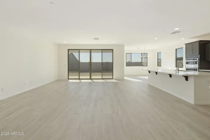 LARGE OPEN GREAT ROOM WITH A 16' SLIDER AND CONTINUOUS WOOD PLANK TILE THROUGHOUT THE GREAT ROOM.