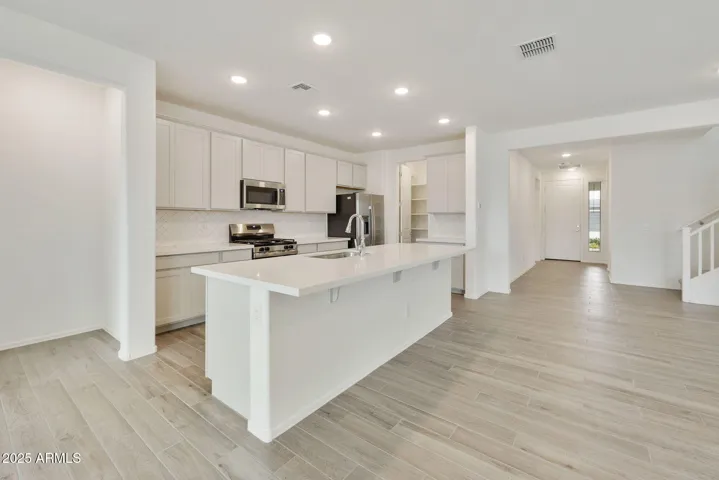 PAINTED CABINETS, QUARTZ COUNTERS, DESIGNER BACKSPLASH, STAINLESS STEEL APPLIANCES AND LARGE WALK IN PANTRY