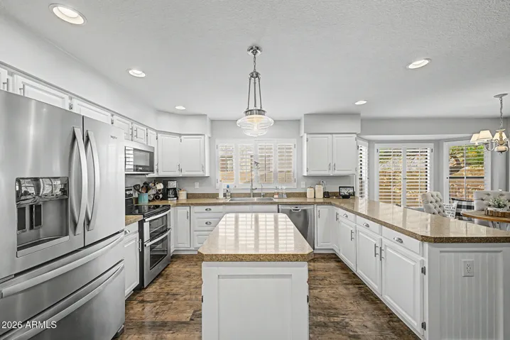 Spacious kitchen filled with natural light, showcasing stainless steel appliances, abundant cabinetry, a functional layout. Plantation shutters and updated finishes enhance this inviting Peoria Home.