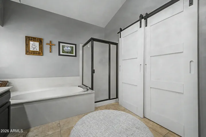 Stylish bathroom featuring sliding barn doors, soaking tub, and separate shower enclosure. This updated space combines functionality with modern design elements.