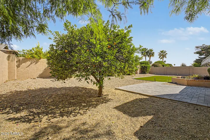Expansive backyard featuring paver patio, artificial turf, and mature landscaping. Designed for easy maintenance, this Peoria home provides ideal outdoor living.