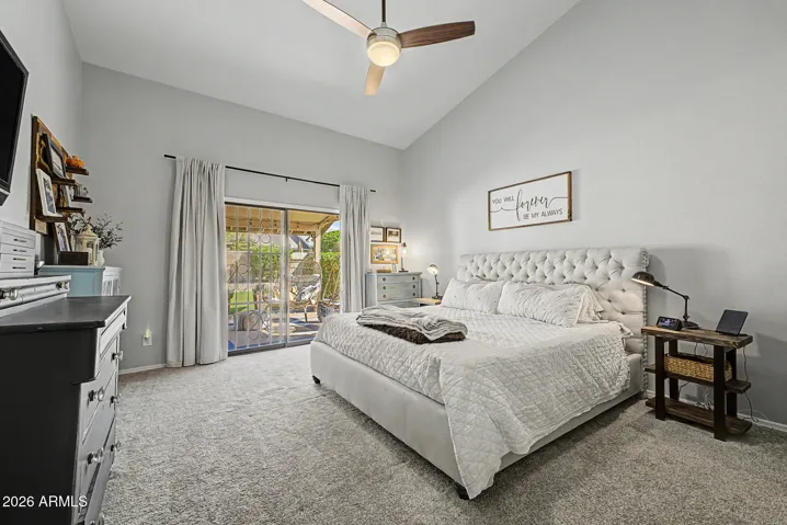 Large primary bedroom with vaulted ceilings, plush carpeting, and direct access to the backyard. This peaceful retreat offers comfort and privacy within this Peoria home.