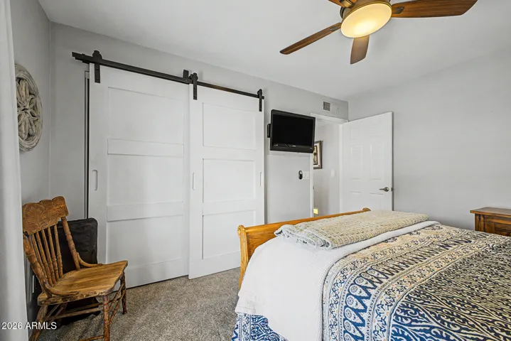 Cozy bedroom featuring stylish barn door closet doors, neautral finishes, and soft carpeting. This Peoria home offers updated details and comfortable living spaces throughout.