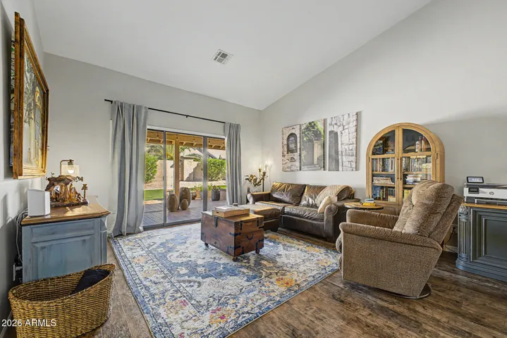 Spacious living room features sliding glass doors that open to the covered patio, blending indoor-outdoor living. Natural light and upgraded flooring enhances this comfortable Peoria home space.