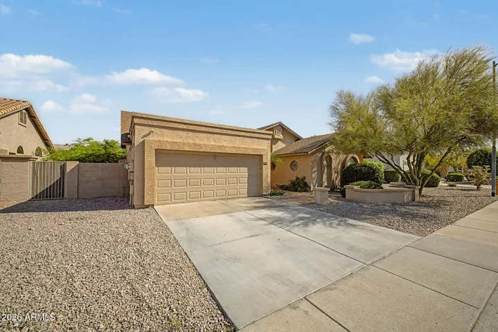 Wide concrete driveway leading to a 2-car garage offers ample parking and convenience. This Peoria home combines functionality with clean exterior design and easy access.