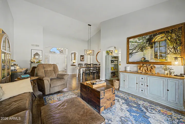 Light-filled living area with soaring vaulted ceilings, wood style flooring, and an open layout. This inviting space connects seamlessly to dining and kitchen area, ideal for modern living in Peoria.