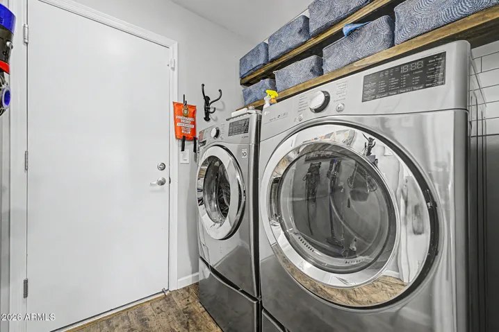 Functional laundry room with front-load washer & dryer, overhead shelving, and organized storage. This Peoria home offers convenience and efficiency for everyday living.