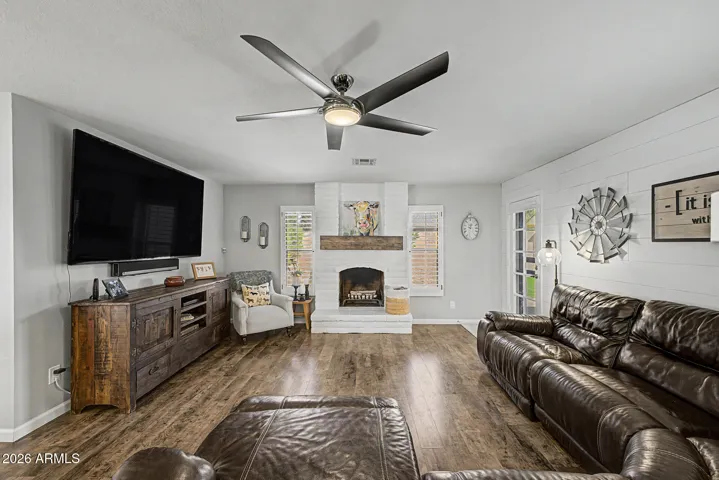 Stylish fireplace with white brick surround and wood mantle creates a stunning focal point. This updated feature enhances the charm & warmth of this Peoria home.