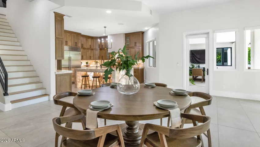 The dining area sits naturally within the great room's open flow, anchored by a warm round table that invites long dinners and easy conversation. The layout connects seamlessly to both the kitchen and the family room beyond, making this a space designed for the way families and guests actually move through a home.