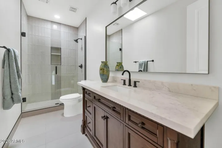 A beautifully finished hall bathroom serves the second floor with a rich dark vanity, light stone countertop, and walk-in glass shower. The same commitment to complete, thoughtful renovation that defines the rest of the home is fully present here.