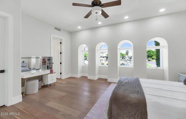 Dramatic arched windows frame a sweeping northward view toward the tennis courts, flooding the room with natural light and creating a connection to the grounds that makes this bedroom feel far larger than its square footage suggests. A room that earns its view.