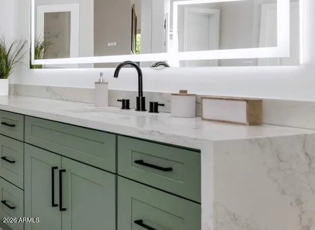 The primary bathroom has been completely reimagined from the ground up. Dual vanities in a rich sage green finish are paired with matte black fixtures and backlit mirrors, creating a spa-like environment that feels both current and enduring. Every detail here was chosen with intention.