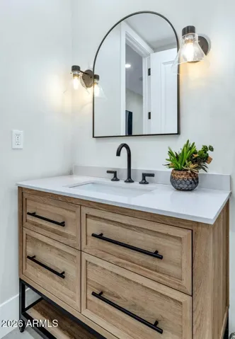 A warm wood vanity, arched mirror, and matte black fixtures give this first-floor guest bathroom a boutique hotel quality that surprises and delights. Every bathroom in this home was fully reimagined — and this one is no exception.