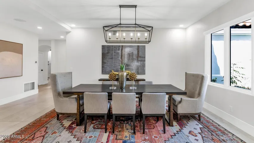The formal dining room is scaled for the moments that matter — holiday gatherings, celebratory dinners, the kind of evenings that become memories. A statement linear chandelier anchors the space above, while large-format porcelain flooring and clean architectural lines keep the aesthetic refined without being austere.